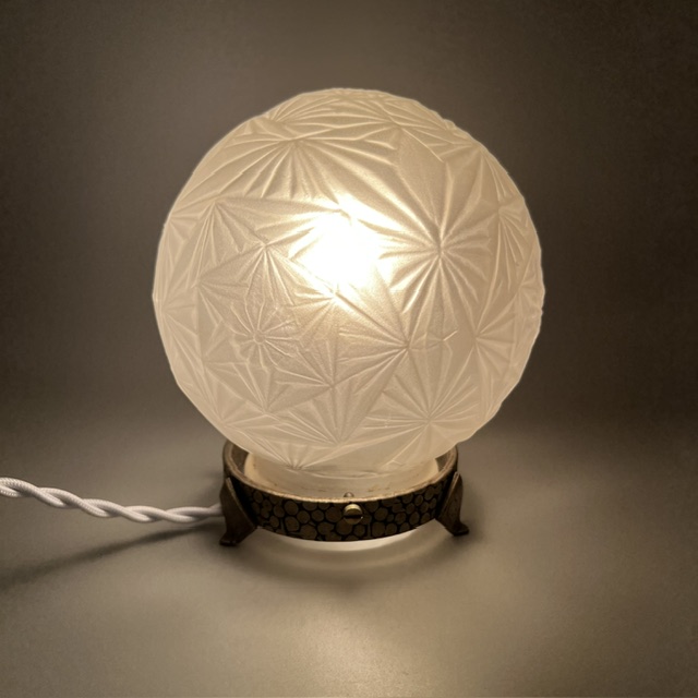 Lampe Art déco signée Sonover allumée, diffusant une lumière douce à travers le globe en verre satiné